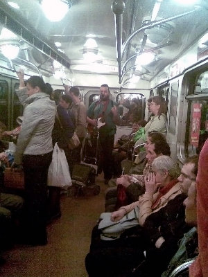 Мужик с гитарой, микрофоном и комбиком в вагоне поезда на первой линии.
